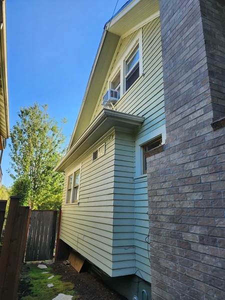 Exterior view of a two-story house with mixed siding materials and brick chimney