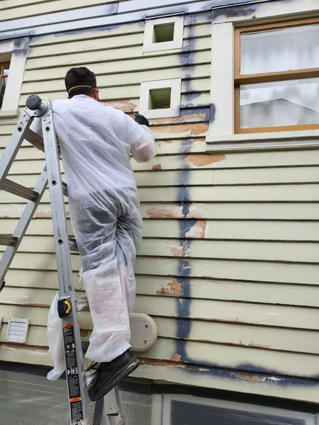 During: worker on ladder removing old siding and prepping wall