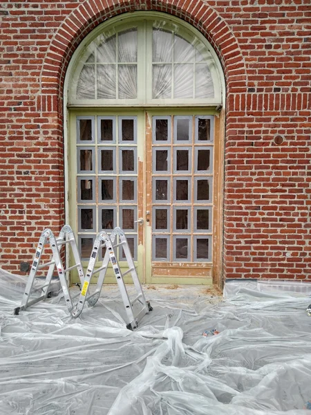 Historic brick building entrance restoration with protective sheeting