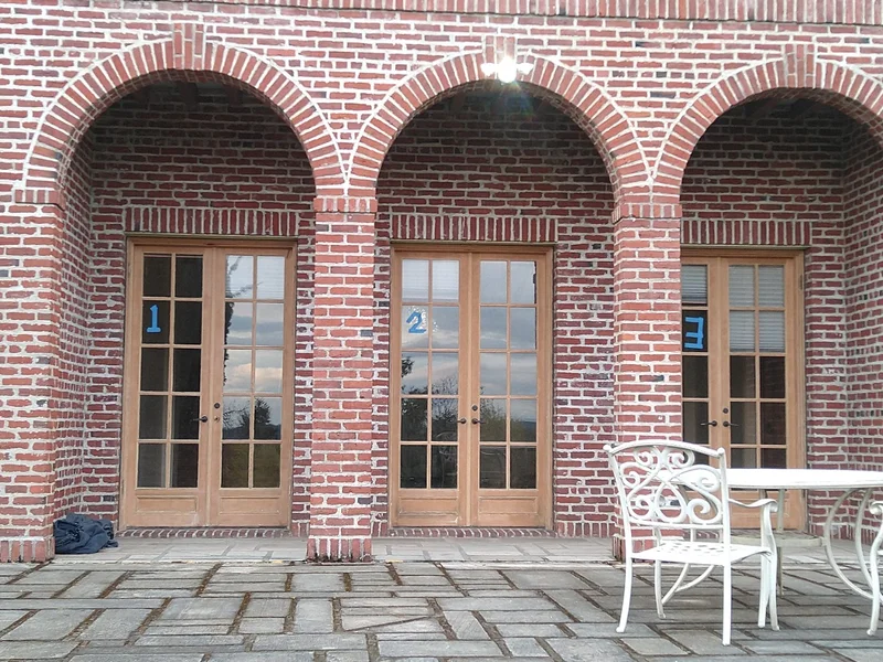 Elegant brick building exterior with arched openings, French doors, and outdoor furniture on stone patio