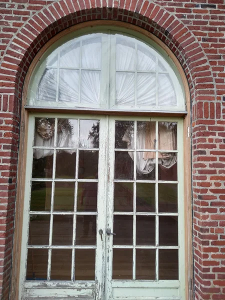 Historic arched window with deteriorating painted shutters