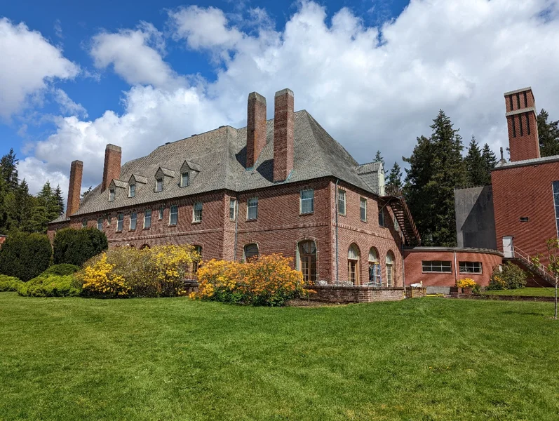 Large historic brick mansion with multiple chimneys and well-maintained grounds